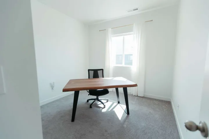 Bright room with large window, neutral carpeting, white walls, and a ceiling vent