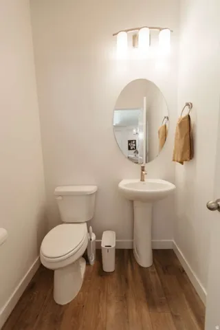 Compact powder room featuring a pedestal sink with a brushed metal faucet, oval mirror, and a three-light vanity fixture