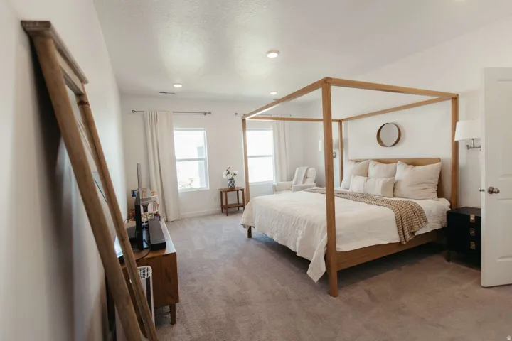 Spacious carpeted room featuring recessed lighting, white walls, and a large window with white curtains