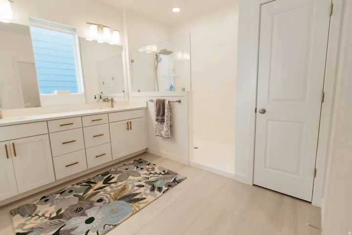 Spacious bathroom featuring a dual vanity with white cabinetry and gold-toned hardware