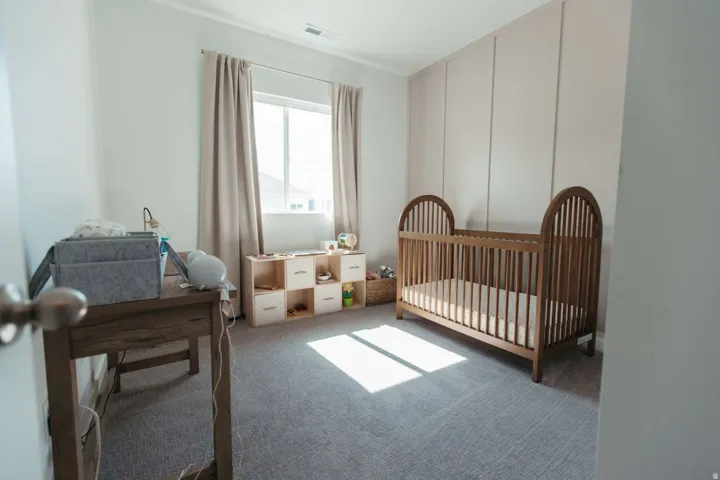 Bright room featuring light gray carpet, a single window with drapes, and a paneled accent wall