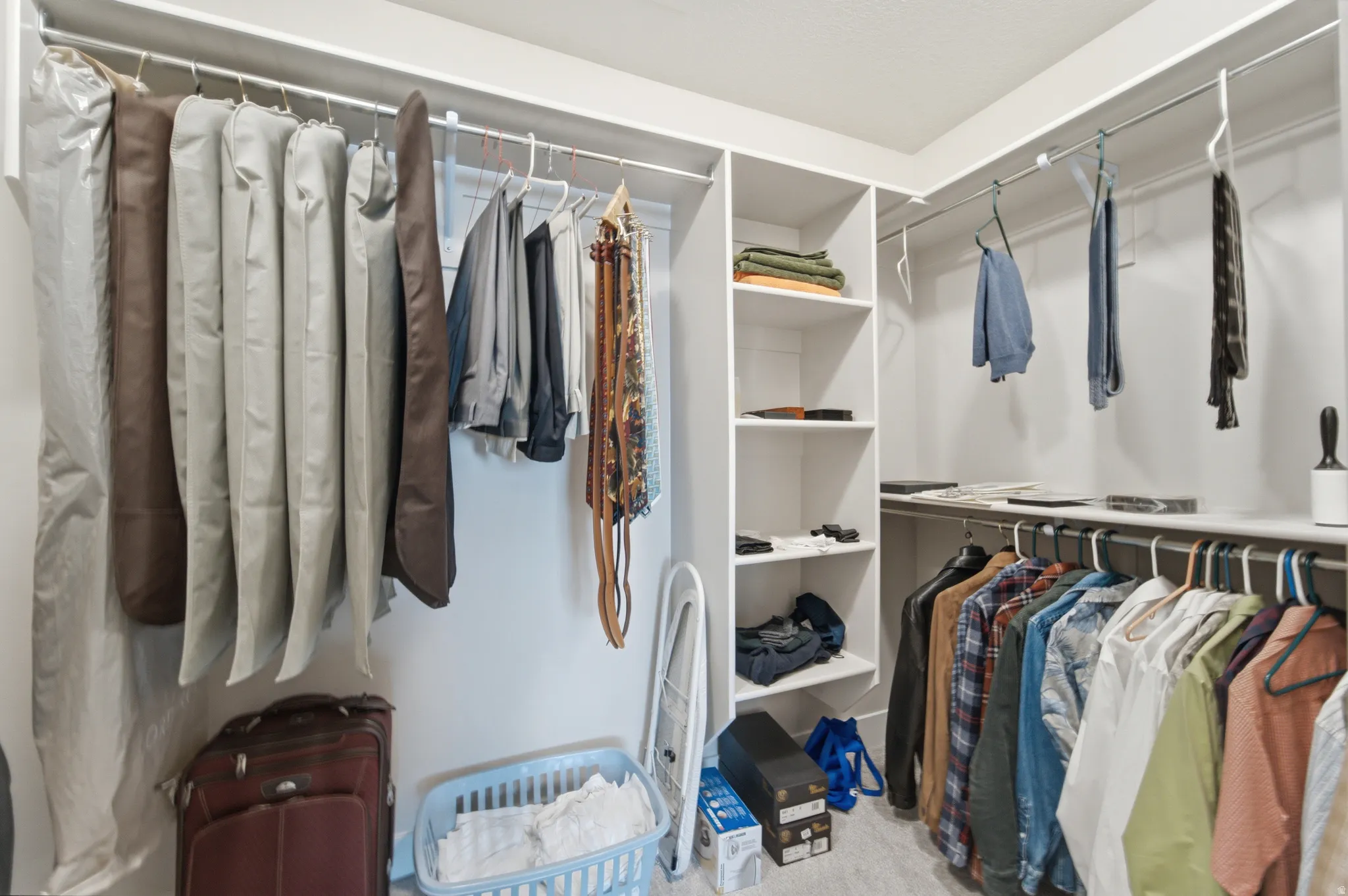 Walk-in closet featuring multiple hanging rods, built-in shelving, white walls, and light-toned flooring