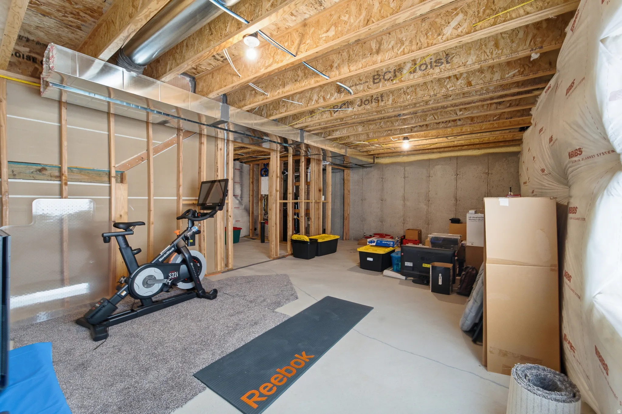 Unfinished basement featuring concrete flooring, exposed wood joists, structural framing, and a concrete foundation wall