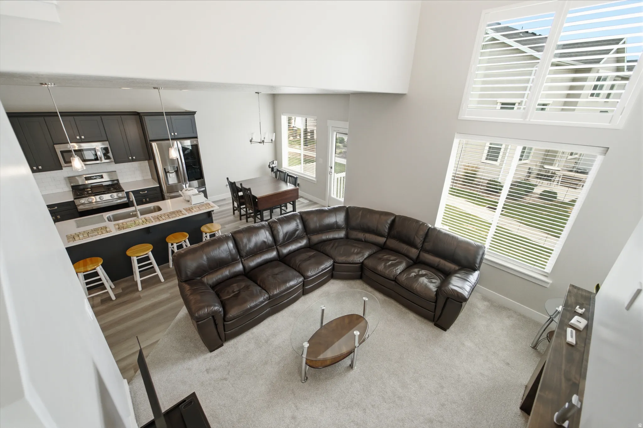 Open-concept living space featuring 2 story tall ceilings, large windows with horizontal blinds, and light gray wall paint