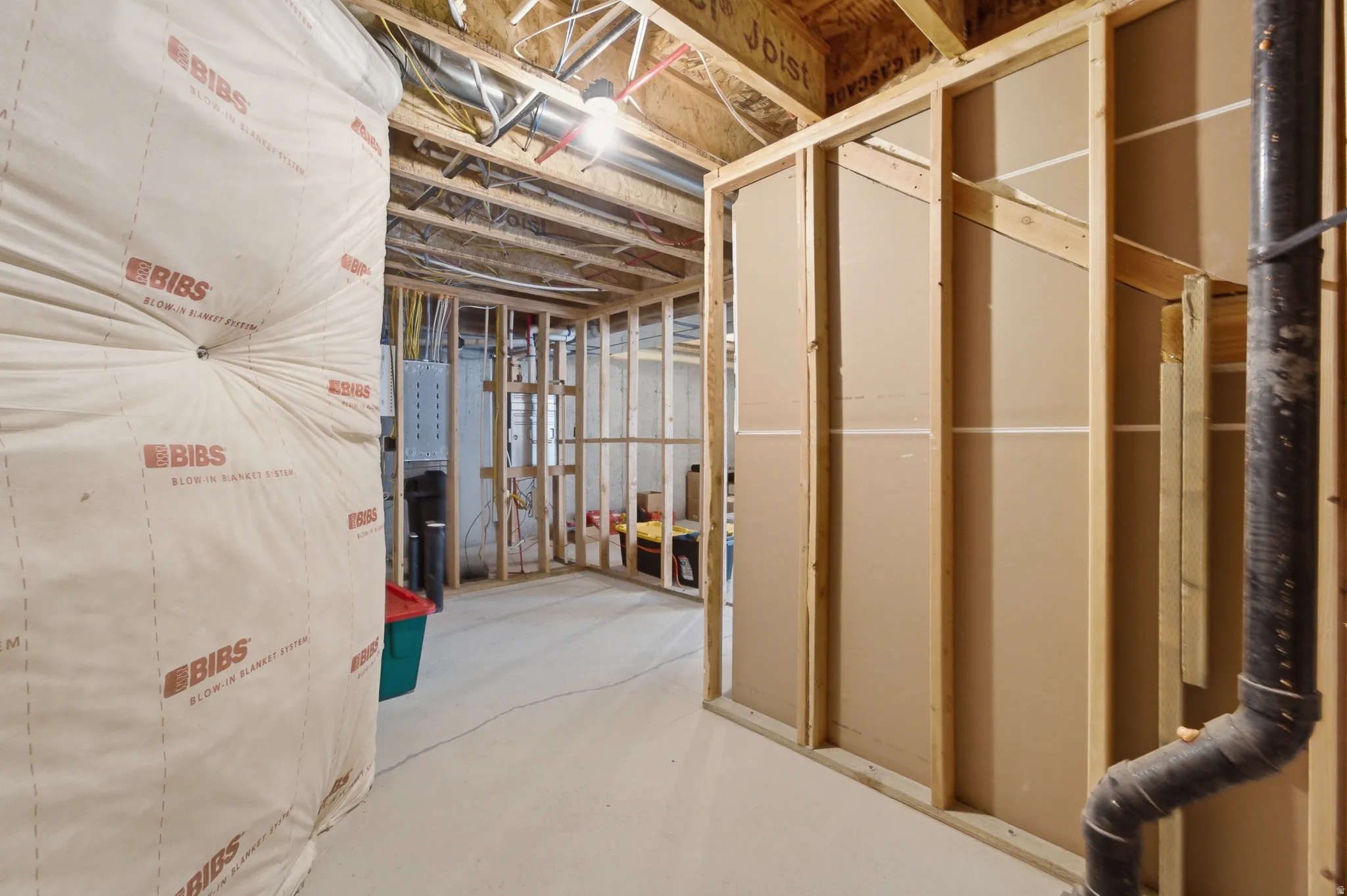 Unfinished basement space featuring exposed wood framing, concrete flooring, and visible insulation