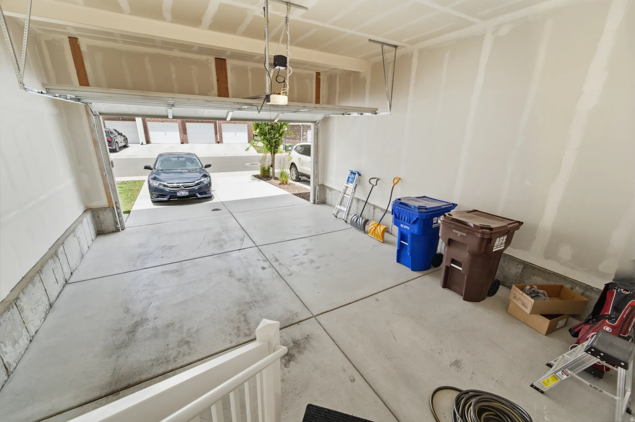 Attached two-car garage with concrete flooring, automatic garage door opener, and unpainted drywall walls