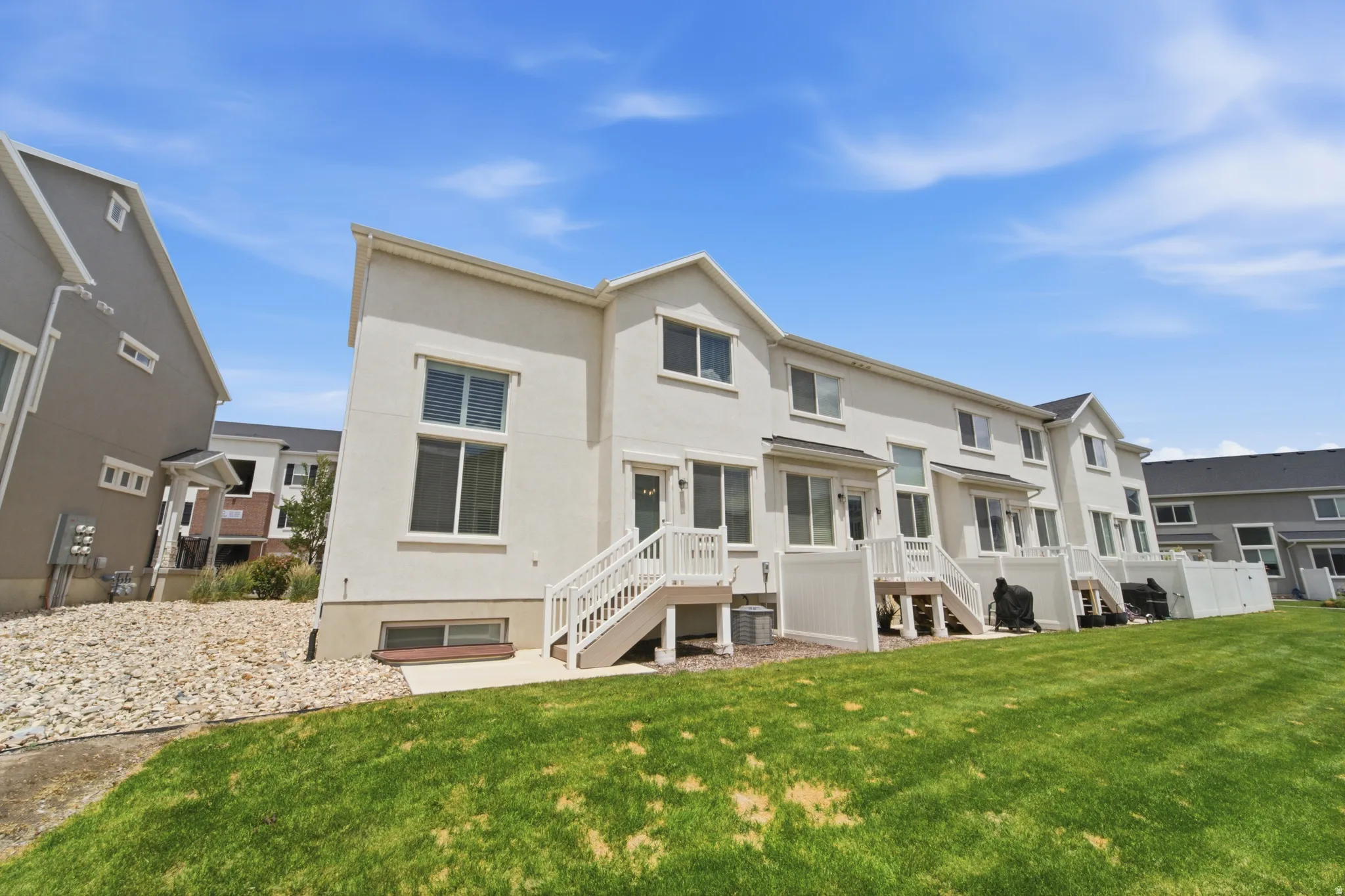 Rear exterior of a multi-story residence featuring light-colored stucco and multiple windows