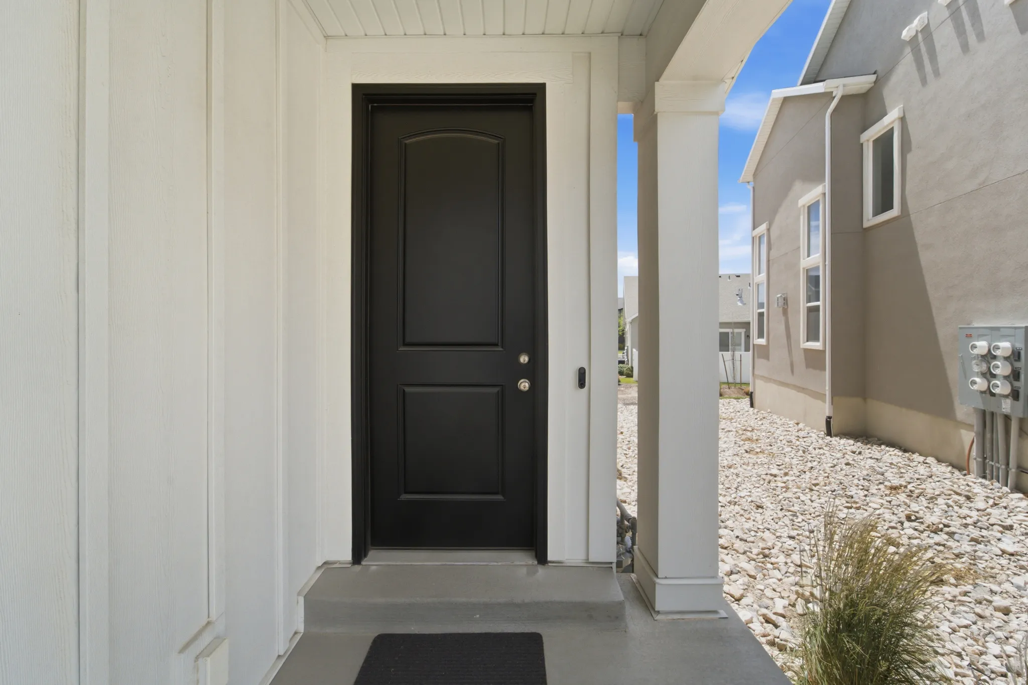 Black panel door with arched top light framing a covered porch entry