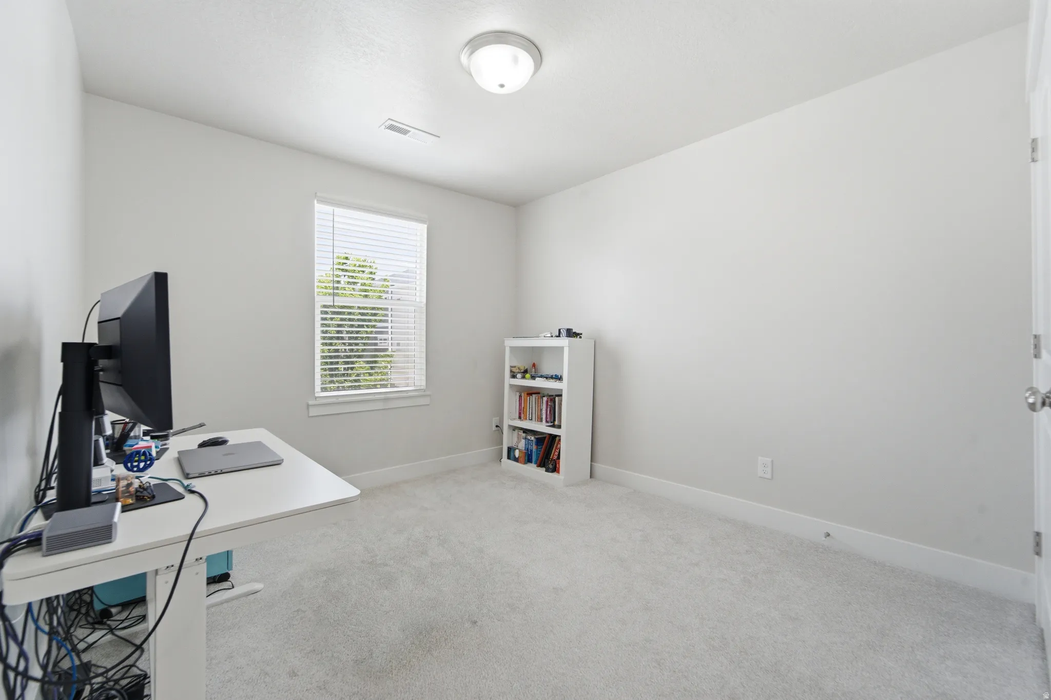 Neutral wall color, window with blinds, and light-toned carpeting