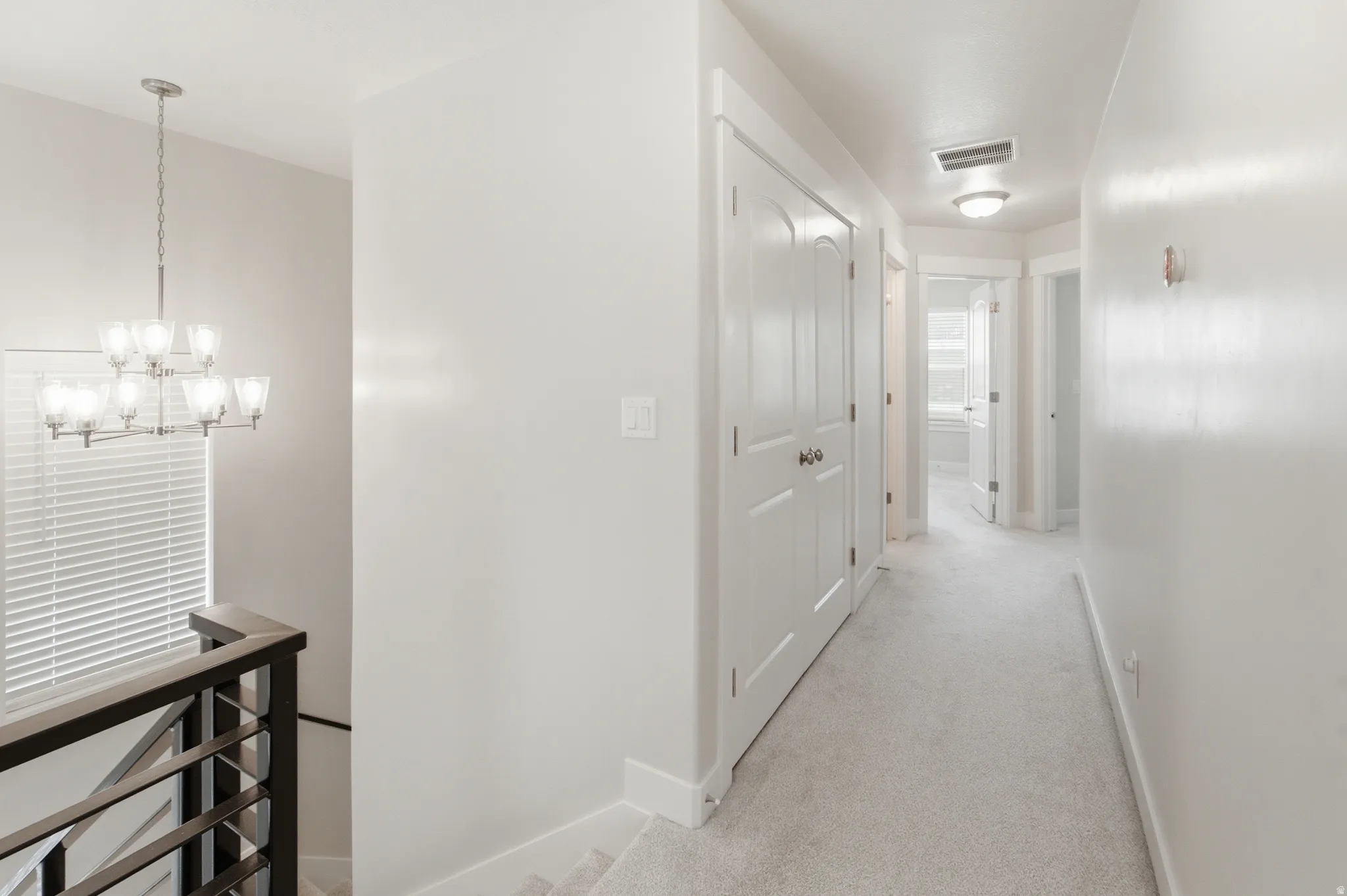 Upper-level hallway with light gray carpet flooring and white painted walls