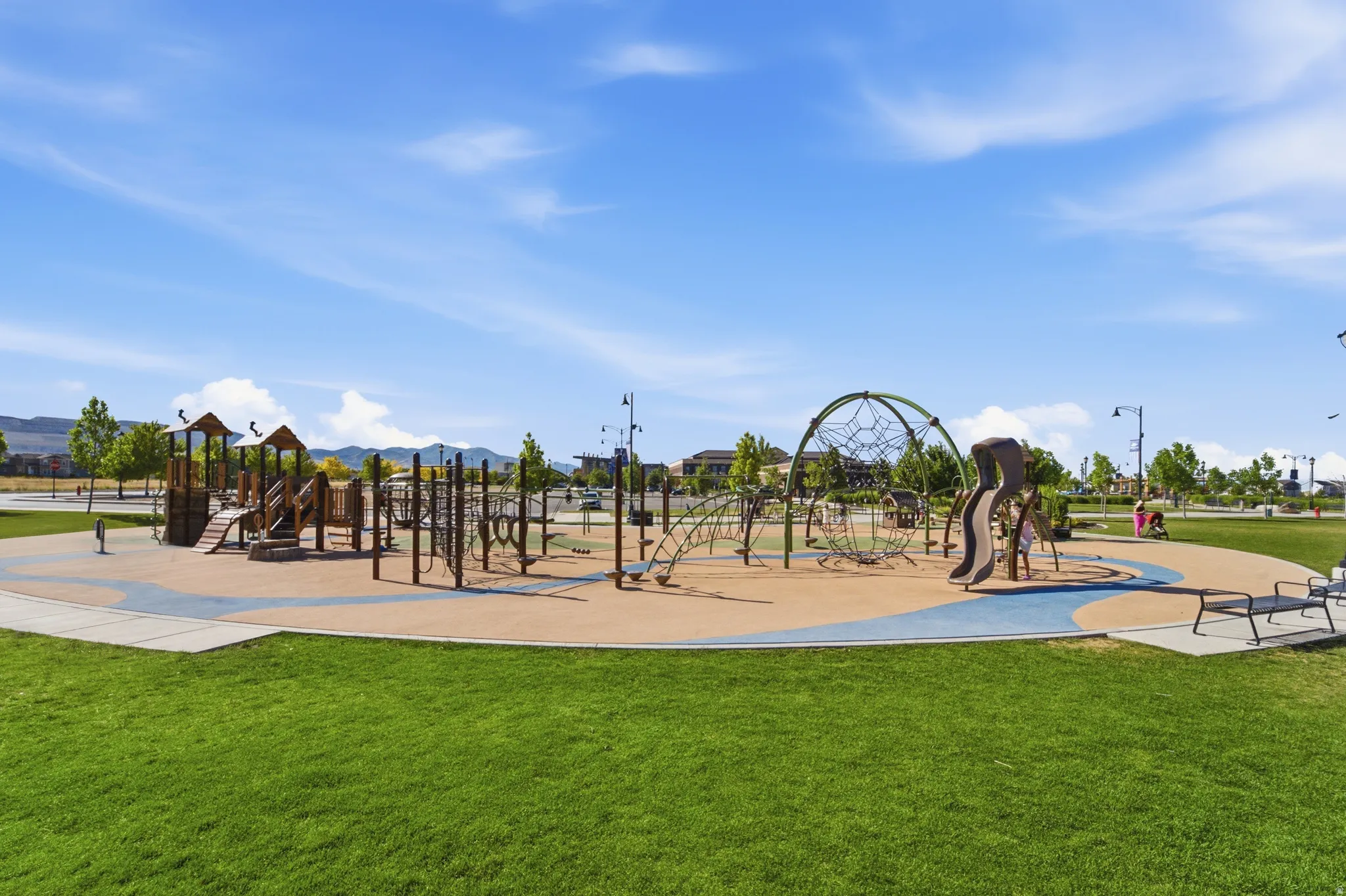 Expansive community park featuring a large playground with multiple structures, climbing features, slides, and swings
