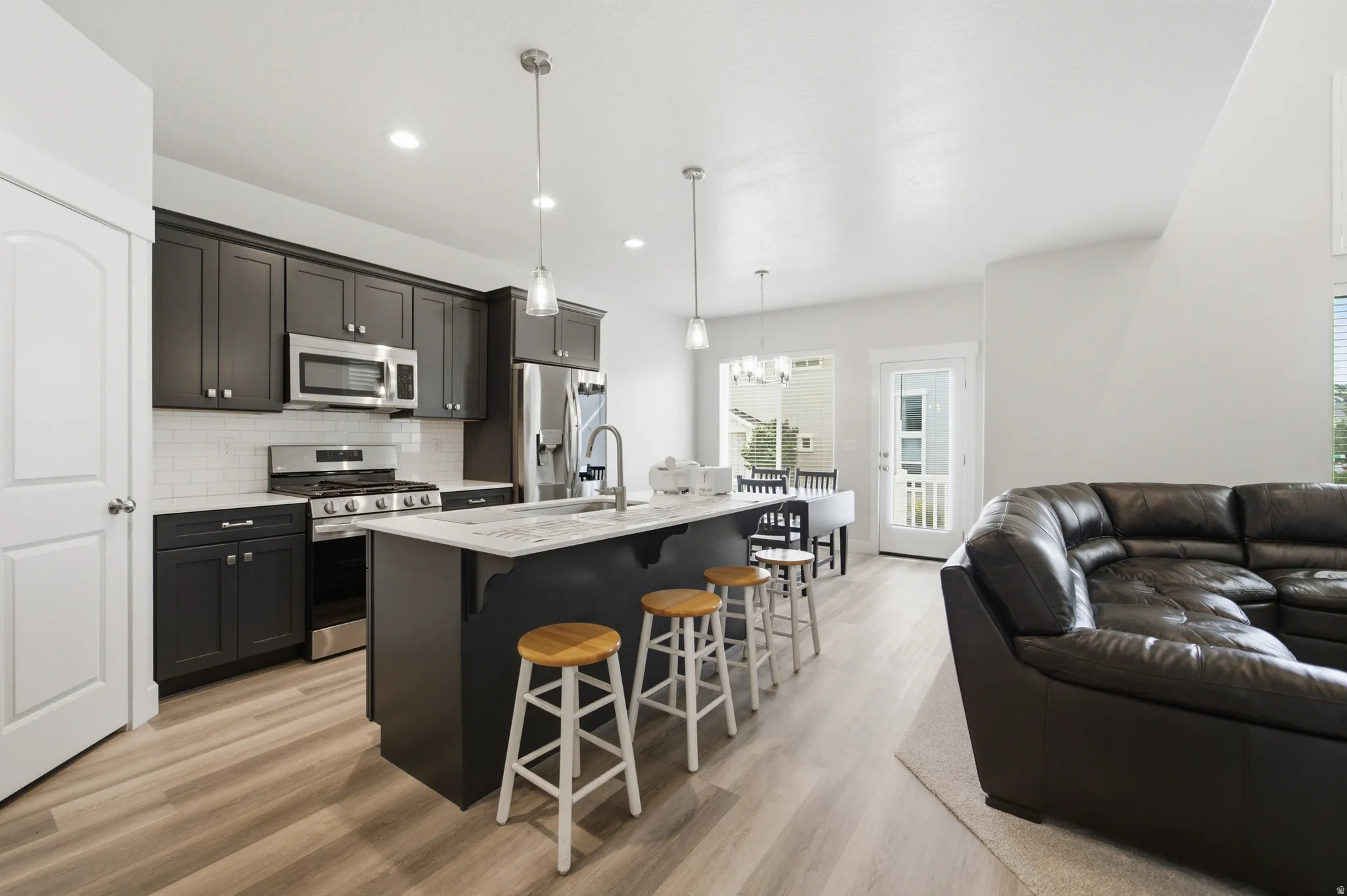 Open-concept kitchen featuring grey/blue cabinetry, stainless steel appliances, and an island with a white stone countertop