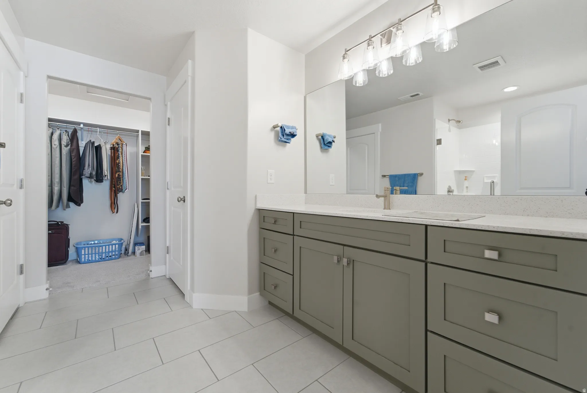 Bathroom vanity featuring a quartz countertop, and extensive storage cabinetry with brushed nickel hardware