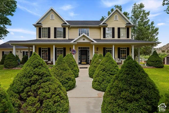 Two-story colonial-style residence featuring yellow siding, a dark roof, and white trim