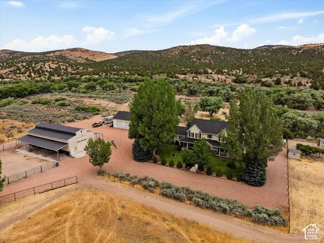 Expansive property featuring a main residence, a large barn, a detached garage, mature trees, and a gravel driveway
