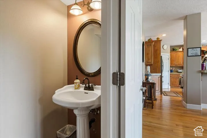 Pedestal sink with bronze-finish faucet, framed oval mirror, and a two-light vanity fixture