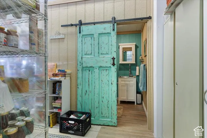 Distressed turquoise barn door with black hardware, opening to a space with vertical paneled walls and wood-finish flooring