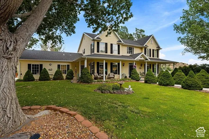 Yellow siding exterior featuring a covered porch, multiple dormer windows, and black window shutters