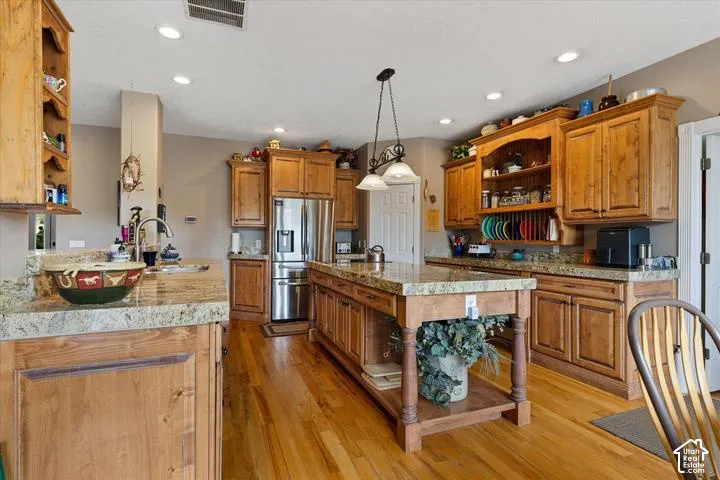 Spacious kitchen featuring natural wood cabinetry, light-toned granite countertops, and wood-finish flooring