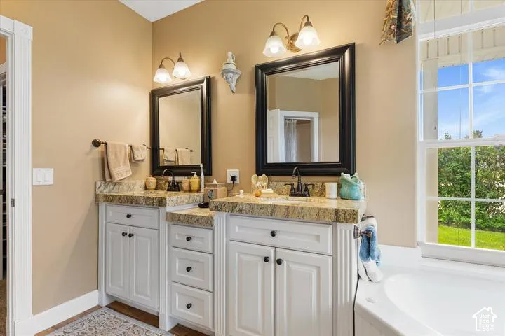 Dual vanity with granite countertops, white cabinetry, and individual framed mirrors