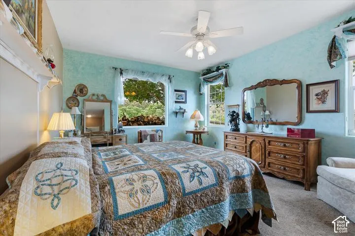 Bedroom with light blue textured walls, two windows, and neutral carpet flooring