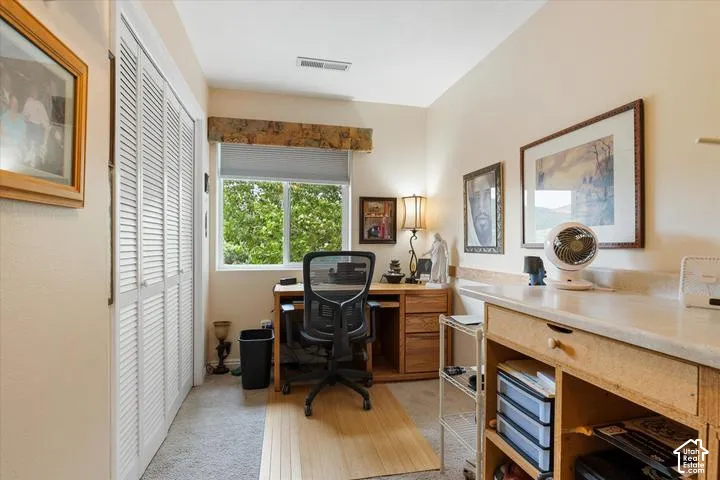 Bright room featuring a window with natural light, neutral wall paint, white louvered bifold closet doors, and mixed flooring with carpet and wood-finish sections