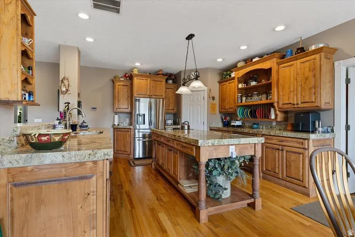 Spacious kitchen featuring natural wood cabinetry, light-toned granite countertops, and wood-finish flooring