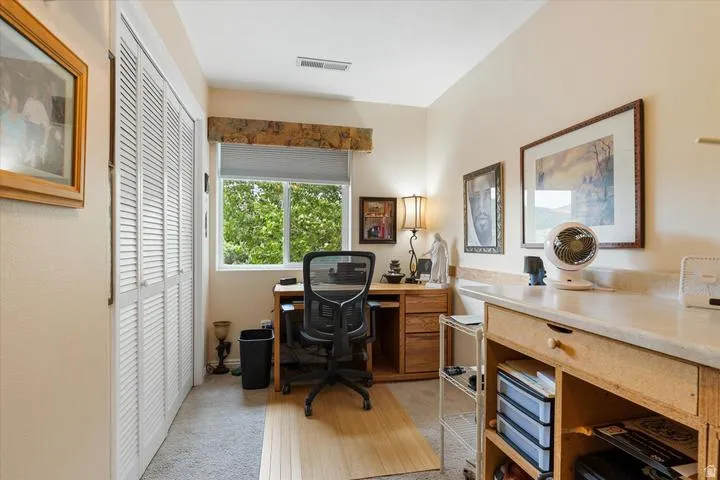 Bright room featuring a window with natural light, neutral wall paint, white louvered bifold closet doors, and mixed flooring with carpet and wood-finish sections