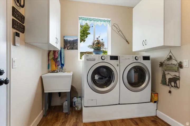 Dedicated laundry space featuring wood-finish flooring and a utility sink