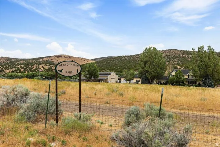Ranch entrance sign featuring a horse motif, set against a backdrop of rolling hills and mature trees