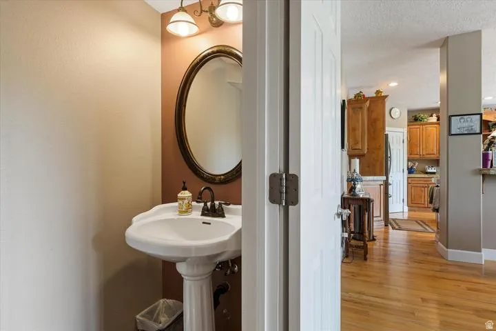 Pedestal sink with bronze-finish faucet, framed oval mirror, and a two-light vanity fixture