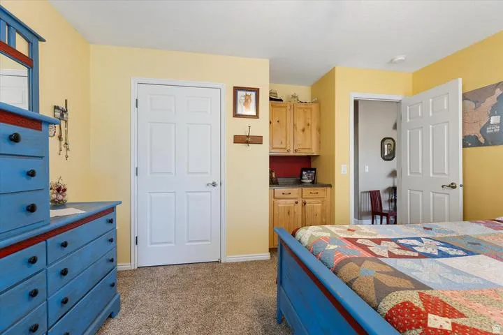 Carpeted room featuring a built-in cabinetry unit with a counter surface and upper cabinets, alongside a six-panel interior door