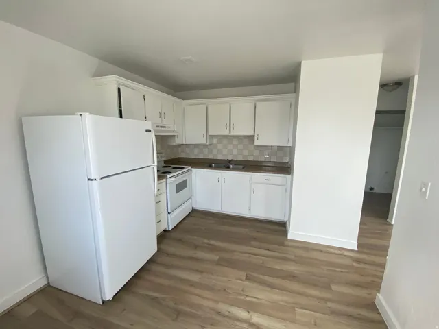 Kitchen featuring white cabinetry, wood-finish flooring, white appliances, a tiled backsplash, and recessed lighting