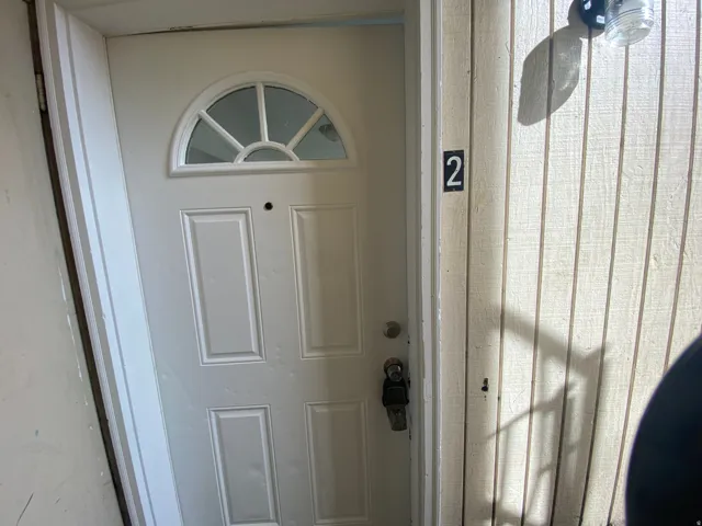 White paneled entry door with an arched transom window and integrated door lock