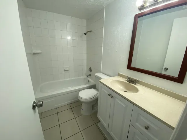 Bathroom featuring a white subway tile shower surround, a white bathtub, and a tile floor