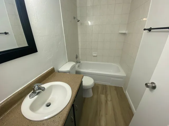 Bathroom featuring a white bathtub with tile surround, a built-in shower head, and a toilet