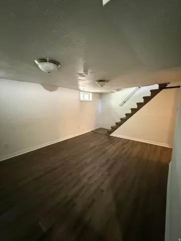 Spacious room featuring wood-finish flooring, white baseboards, and neutral wall tones