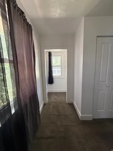 Hallway featuring neutral-toned carpeting, white walls, and white trim