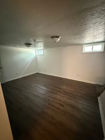 Spacious room featuring wood-finish flooring and white baseboards
