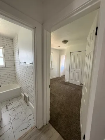 Bathroom featuring subway tile shower surround and marble-look floor tiles