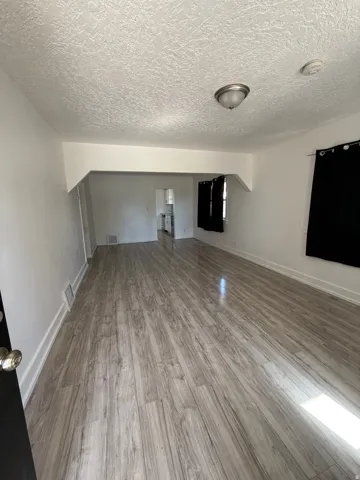 Open-concept living area featuring wood-finish flooring, white painted walls, and a semi-flush mount ceiling light