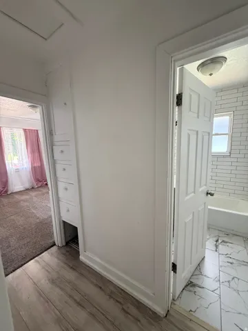Hallway featuring wood-finish flooring, built-in cabinetry, and white paneled doors