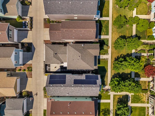 Aerial view showcasing residential properties with diverse roofing materials including asphalt shingles and solar panels