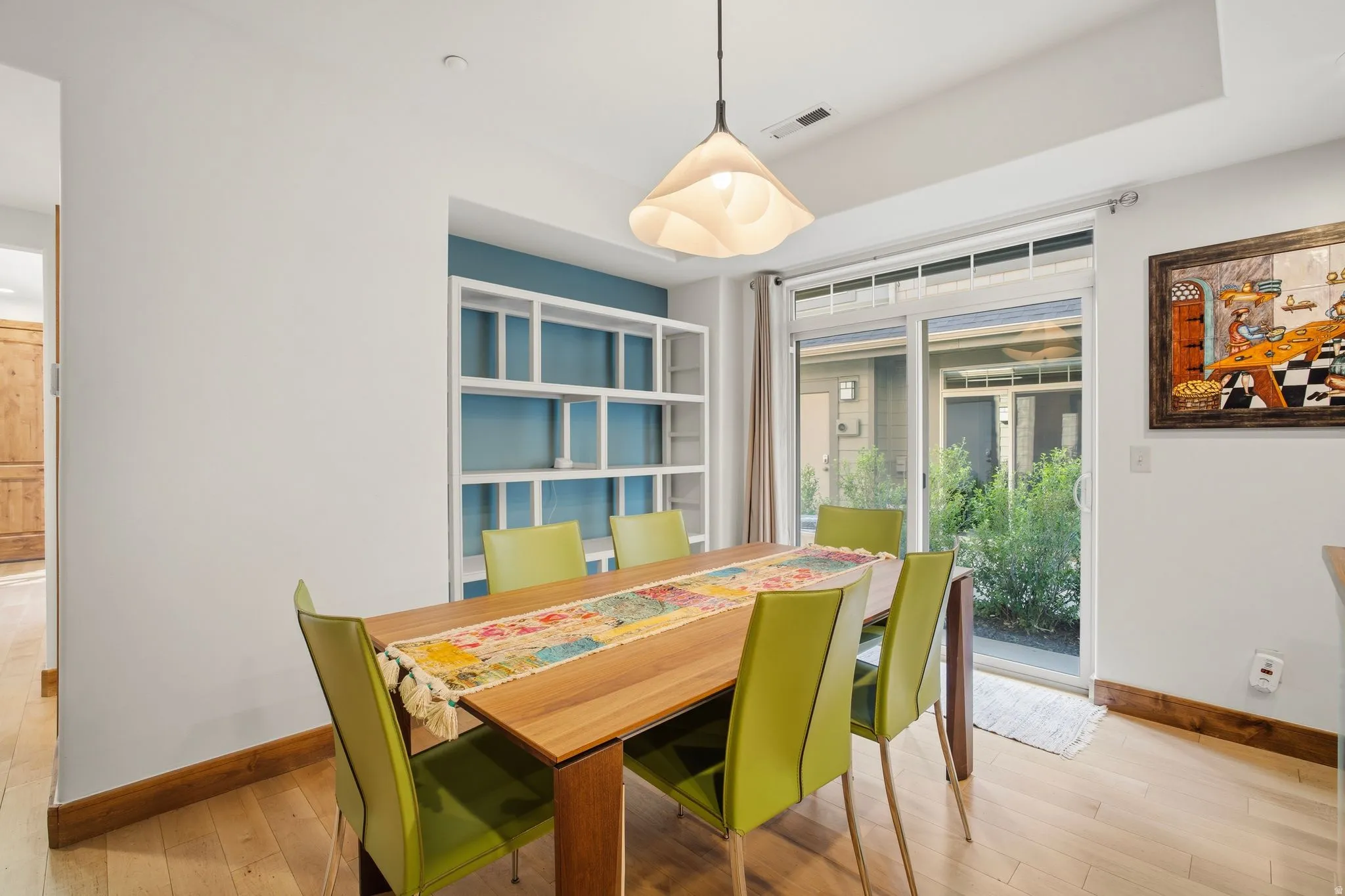 Dining area featuring light wood-finish flooring and a contemporary pendant light fixture