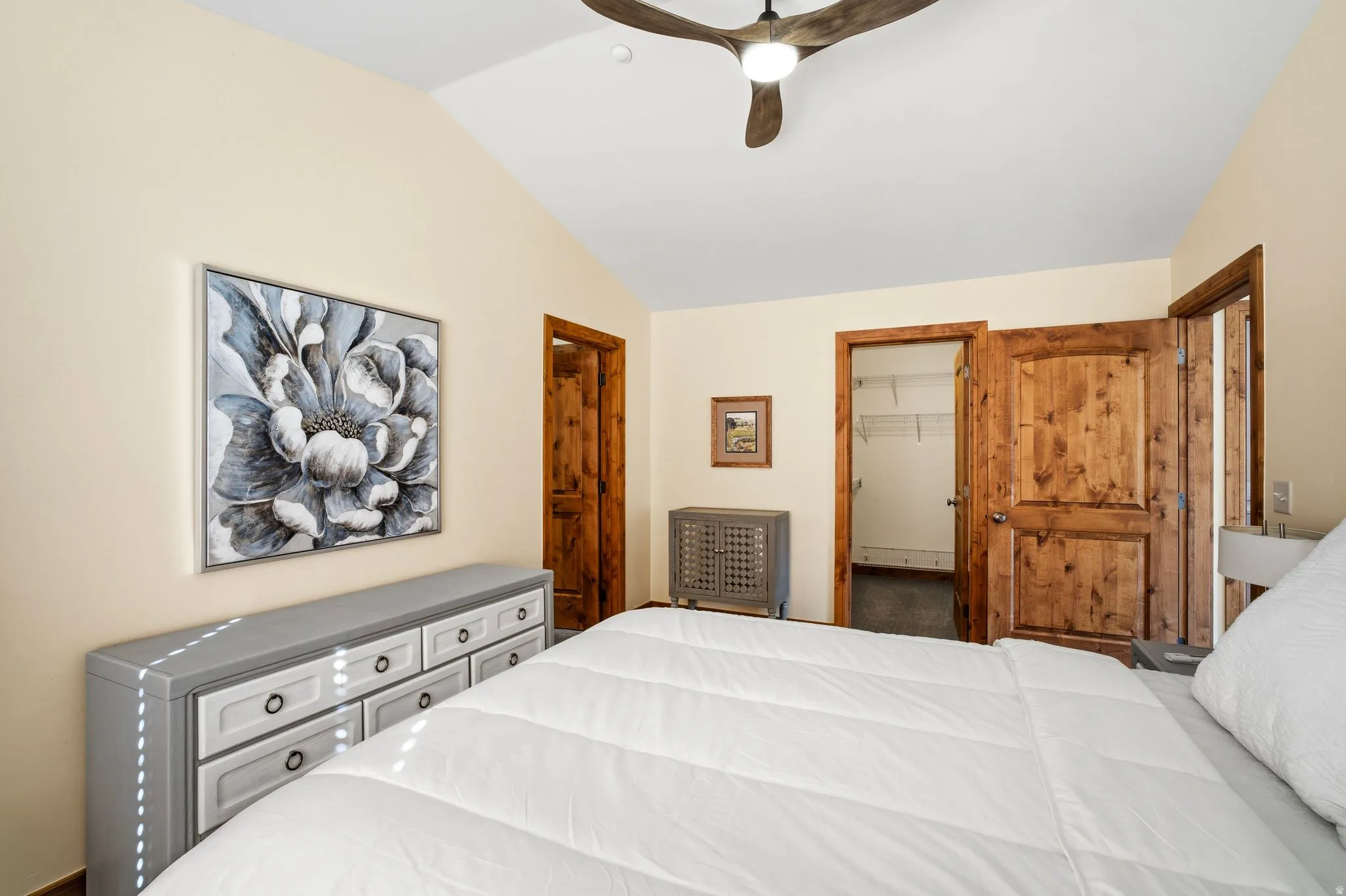 Vaulted ceiling with a wood-finish ceiling fan, natural wood doors, and a built-in closet with shelving
