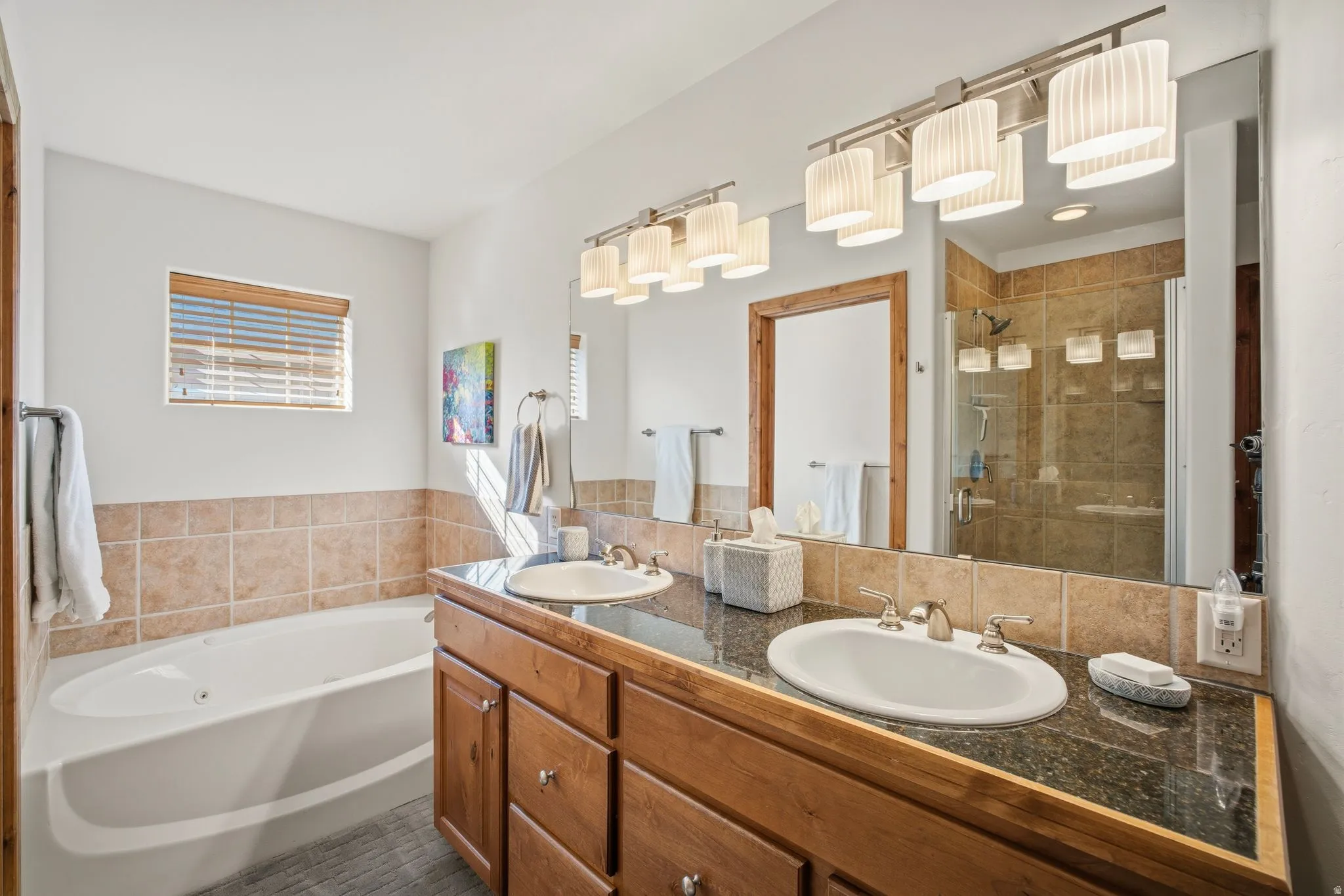 Bathroom featuring a deep soaking tub, dual vanity with undermount sinks, and a walk-in shower with glass enclosure