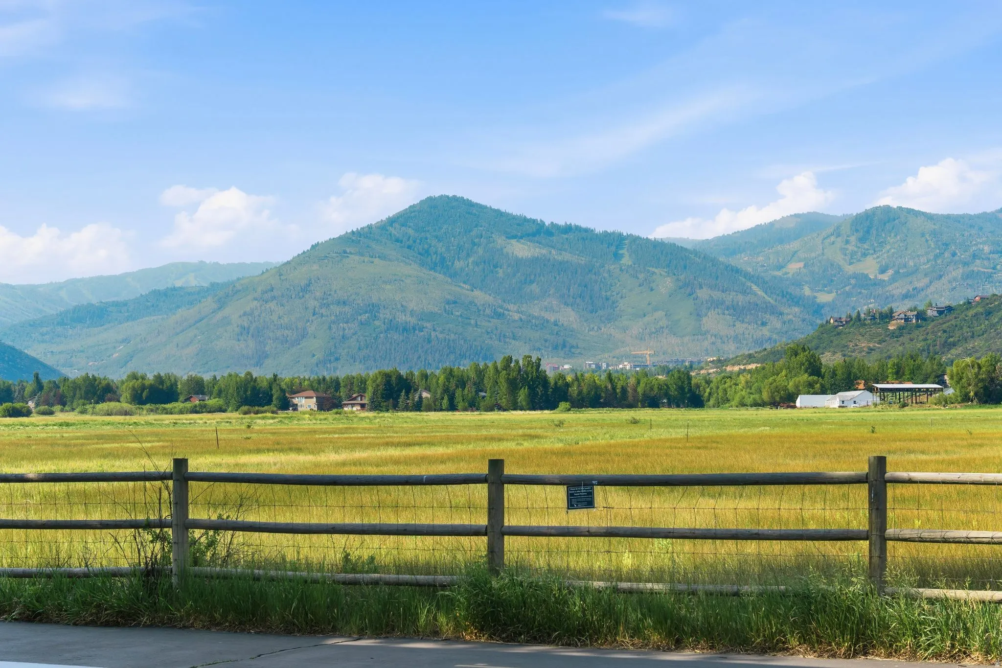 Extensive open field with distant mountain ranges and scattered residential structures