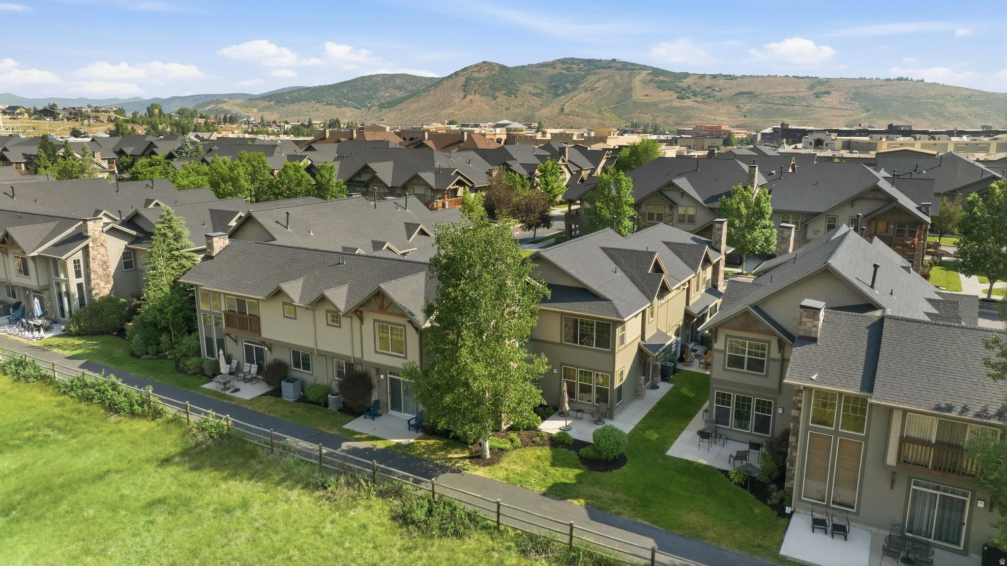 Residential community featuring multi-story properties with dark shingle roofs, balconies, and ground-level patios