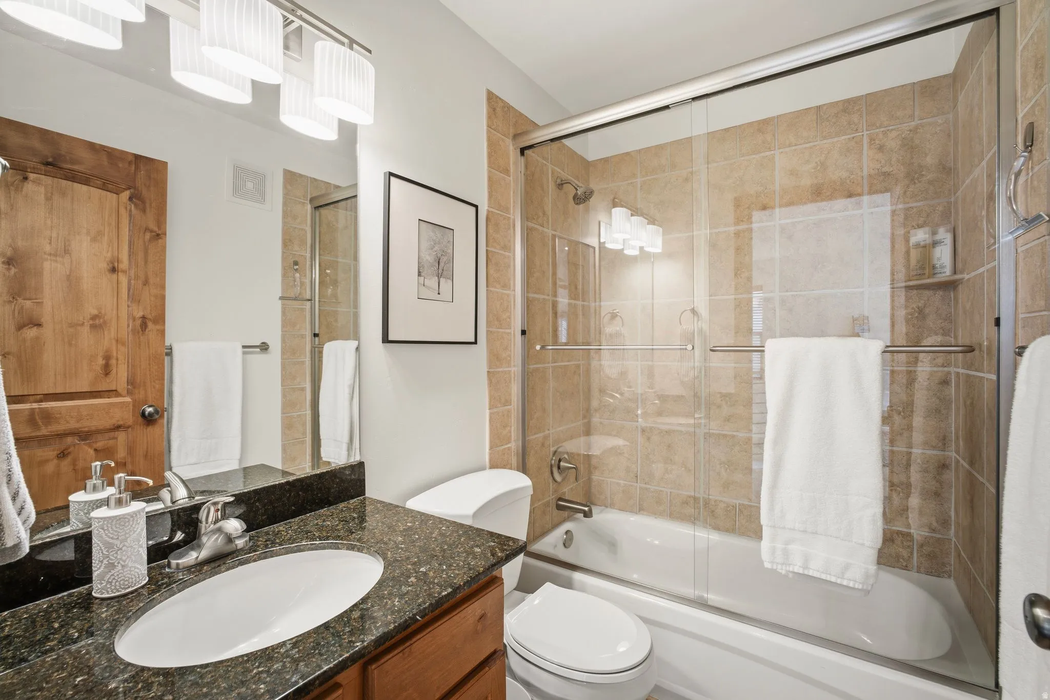 Bathroom featuring a vanity with a dark speckled countertop, an undermount sink, and a chrome faucet