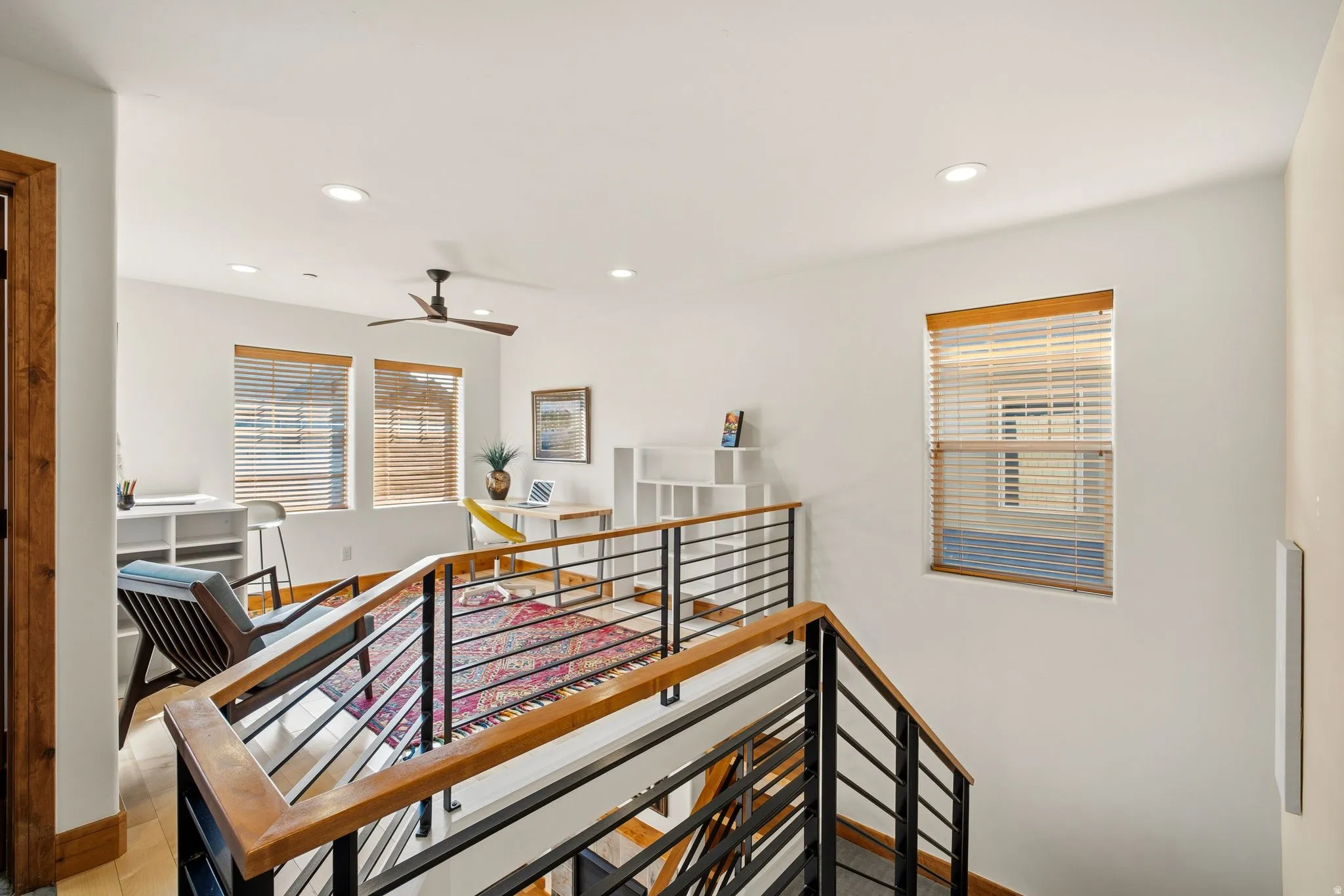 Upper-level landing featuring a contemporary railing with wood-finish handrails and black metal balusters